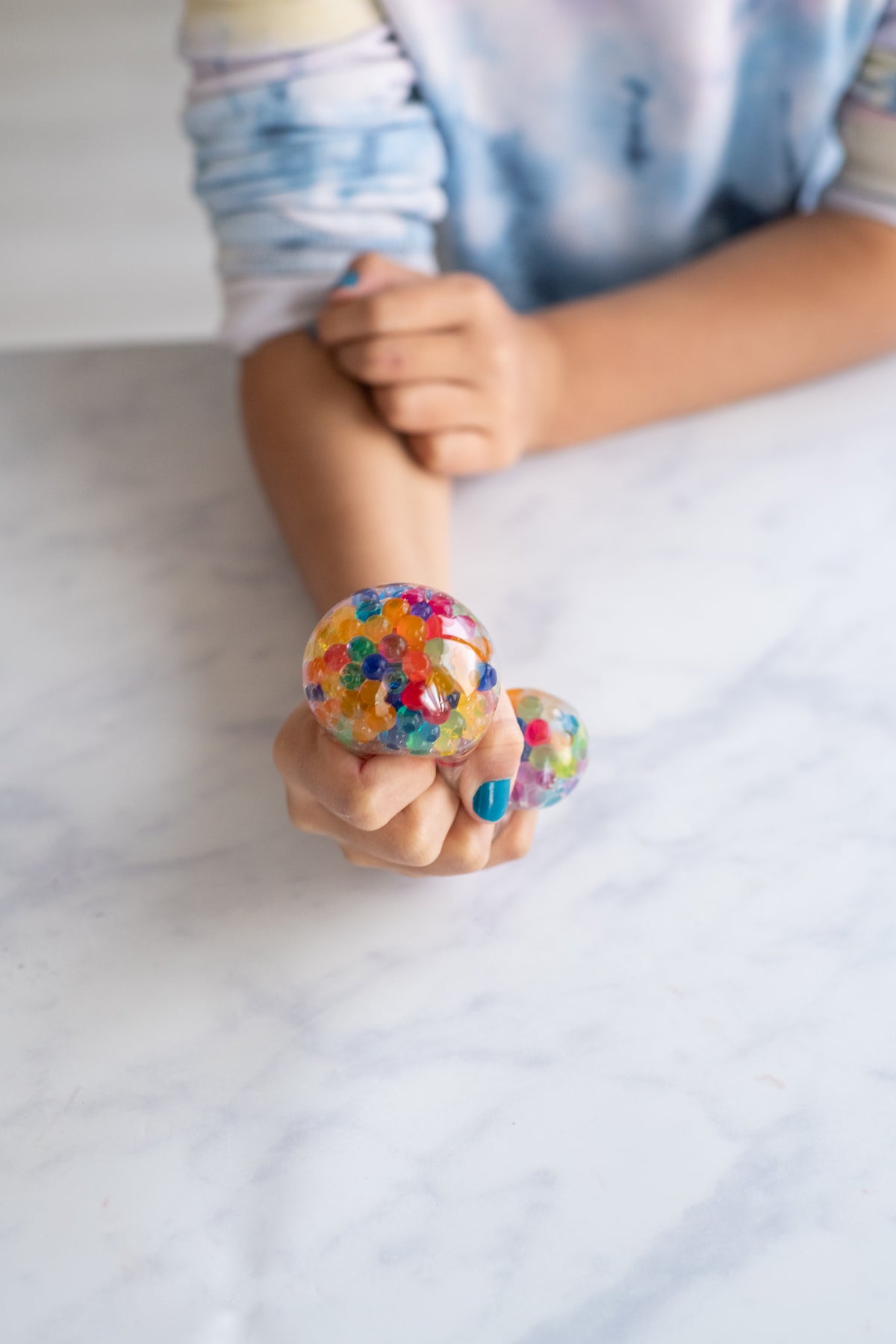 Multi colour jelly bead stress ball squeezed in a child's hand