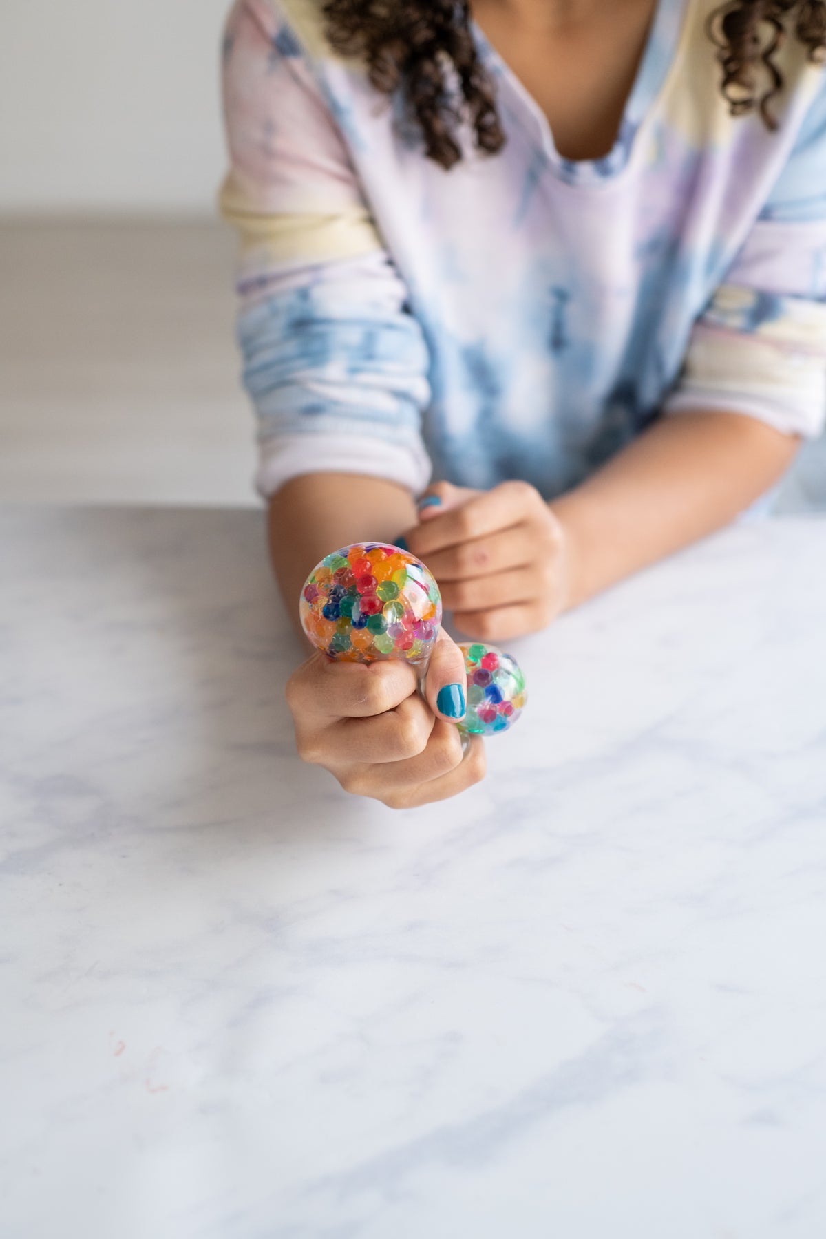 Child squeezing a multi colour jelly bead stress ball
