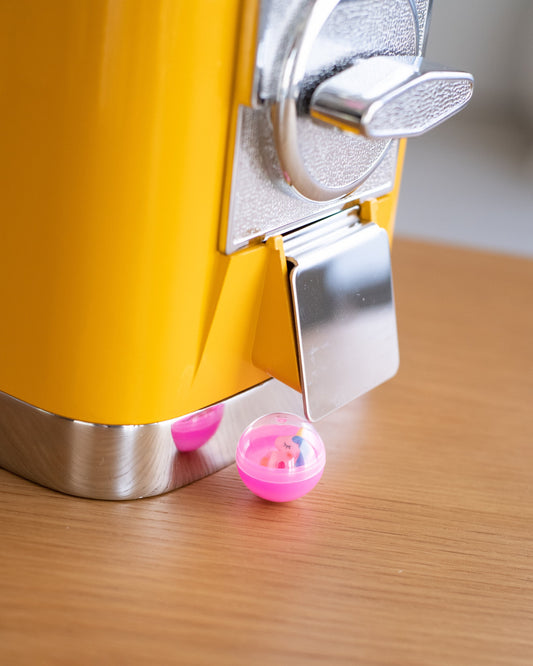 Mystery slime charm capsule coming out of a yellow gumball machine — Lil' Slimetastic