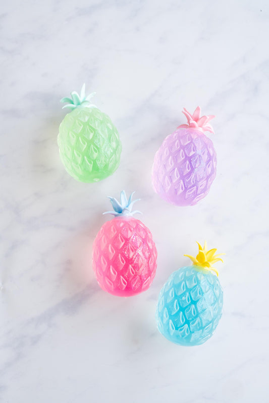 Four sparkly pineapple squishy stress balls in green, purple, pink and blue